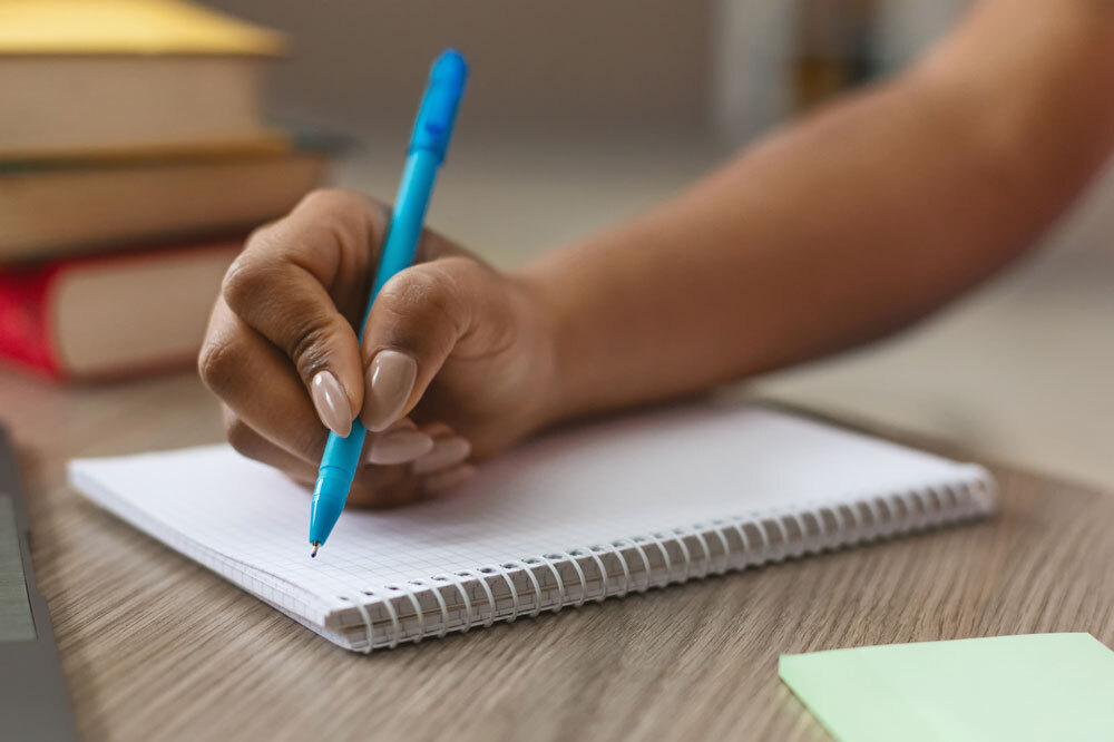writing or planning - teen hand with a notebook and pen
