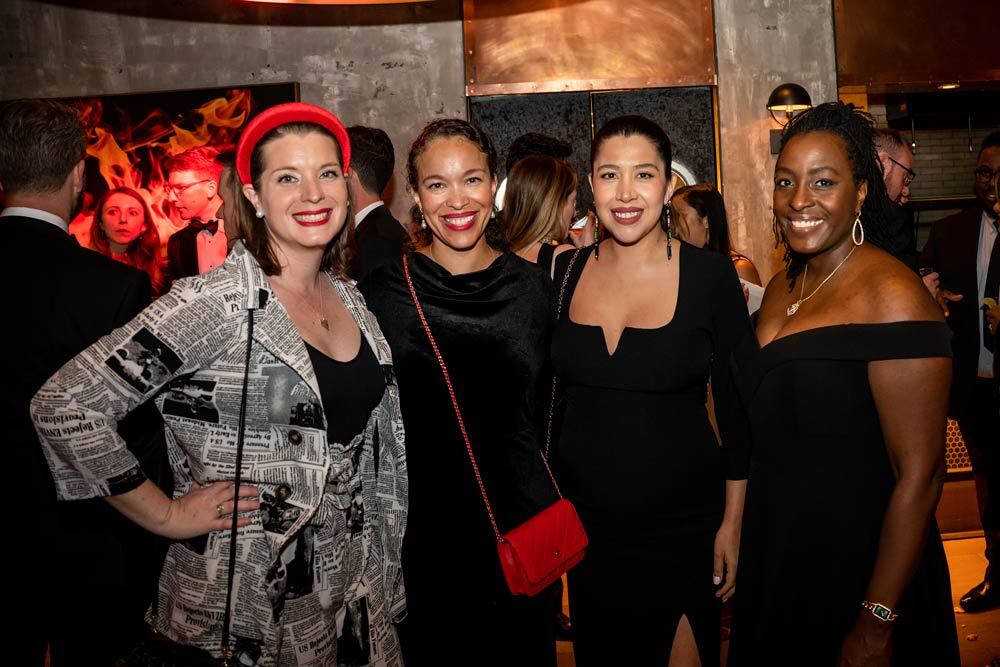 a group of people posing at the 2022 Black & White Party, one has a newspaper print dress