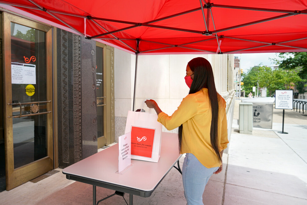 Sidewalk Service - customer with a mask picking up library materials