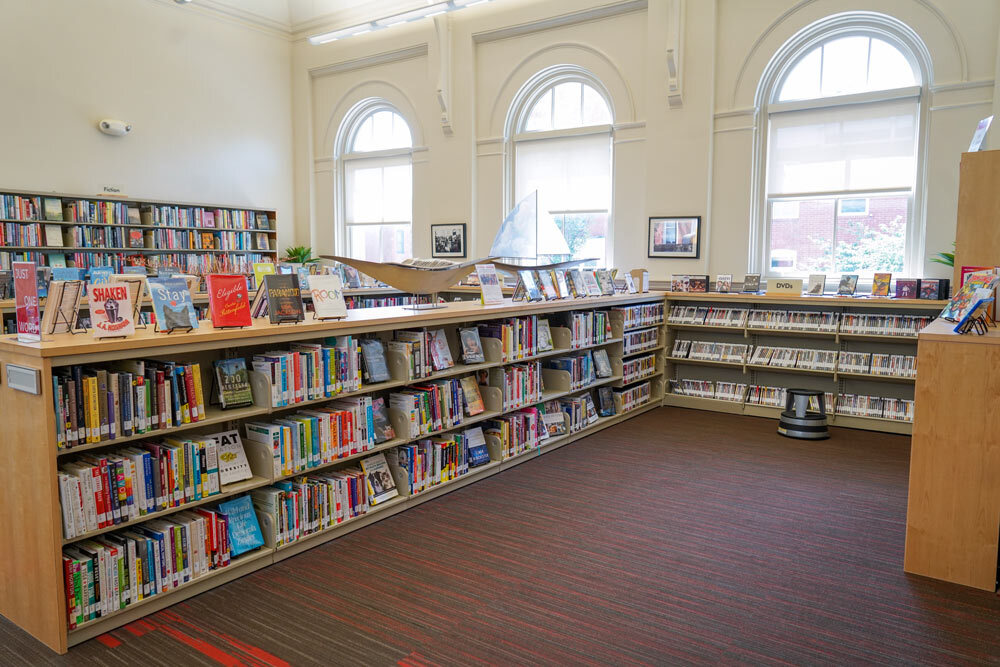 Canton interior view of a library room with books on display and natural light from arched windows