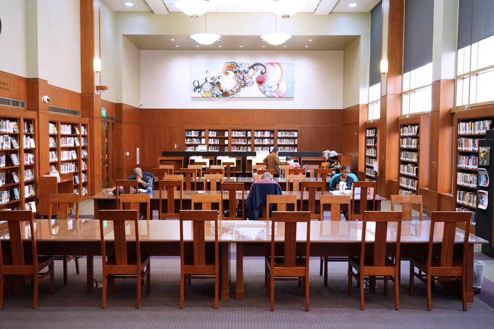 Central Library - African American Department reading room with bookshelves, wooden chairs, and glass-topped wooden tables