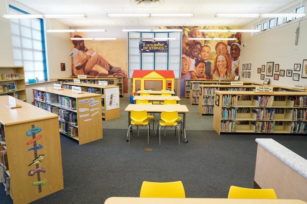 Edmondson Avenue - children's area with books sections, tables and chairs, and artwork on the wall form a children's book