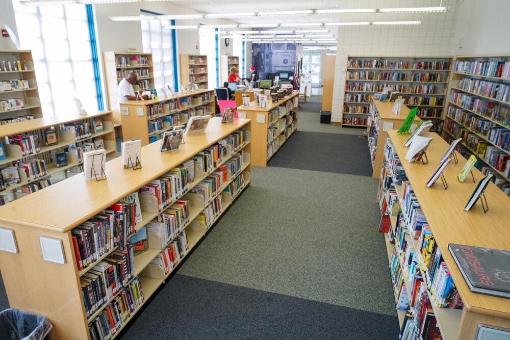 Edmondson Avenue - wide room view with adults browsing, bookshelves, windows