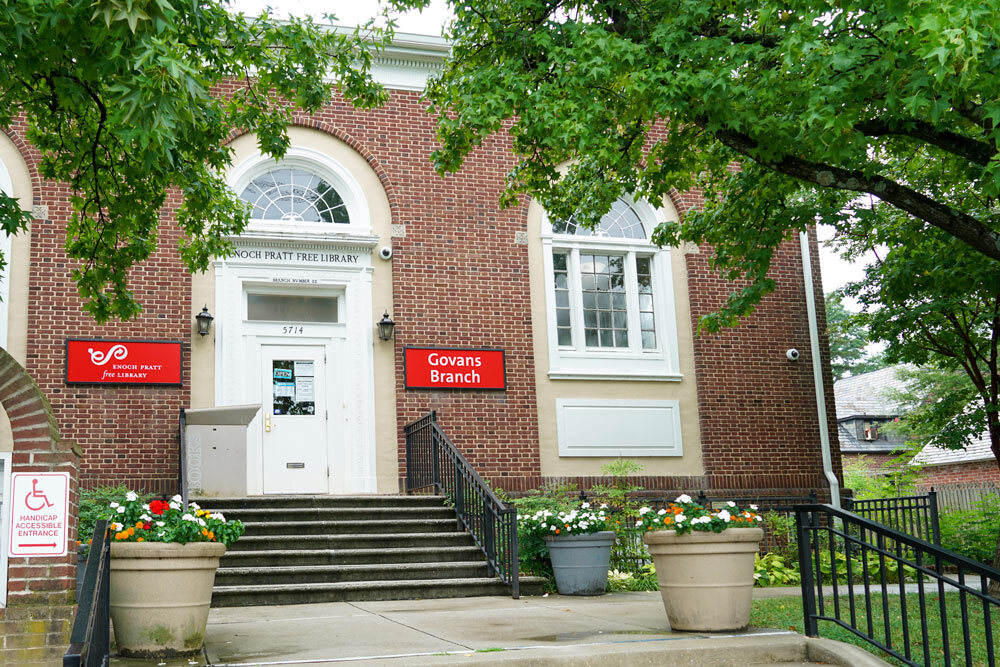 Govans exterior entrance - red signs, doors, steps, and flowers