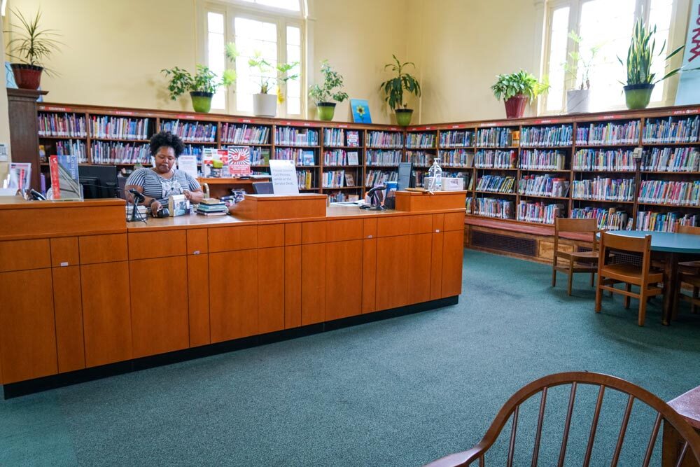 Govans staff at desk, bookshelves, windows, plants