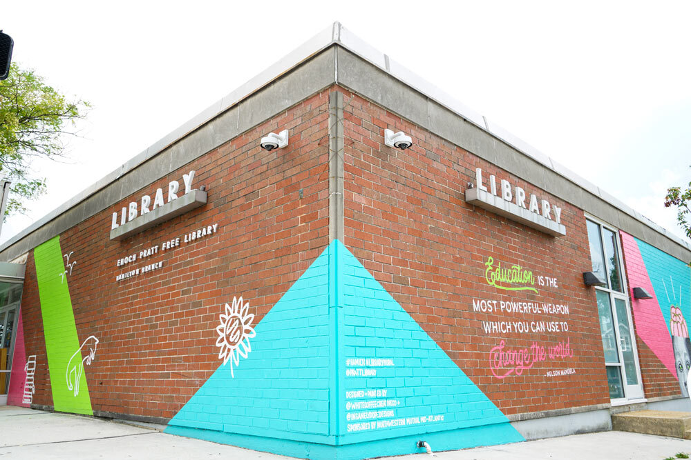 Hamilton - exterior corner view with Library sign and painted murals with quotes on brick walls