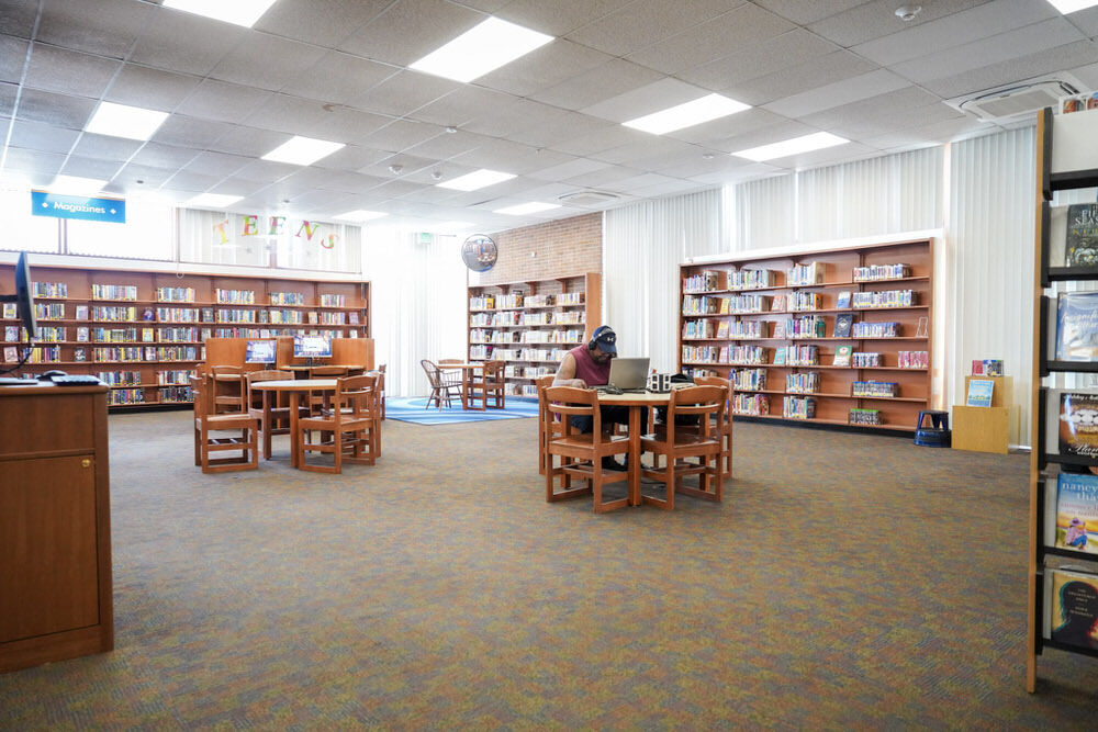 Northwood Branch room with bookshelves and a man using a laptop at a table with device charging