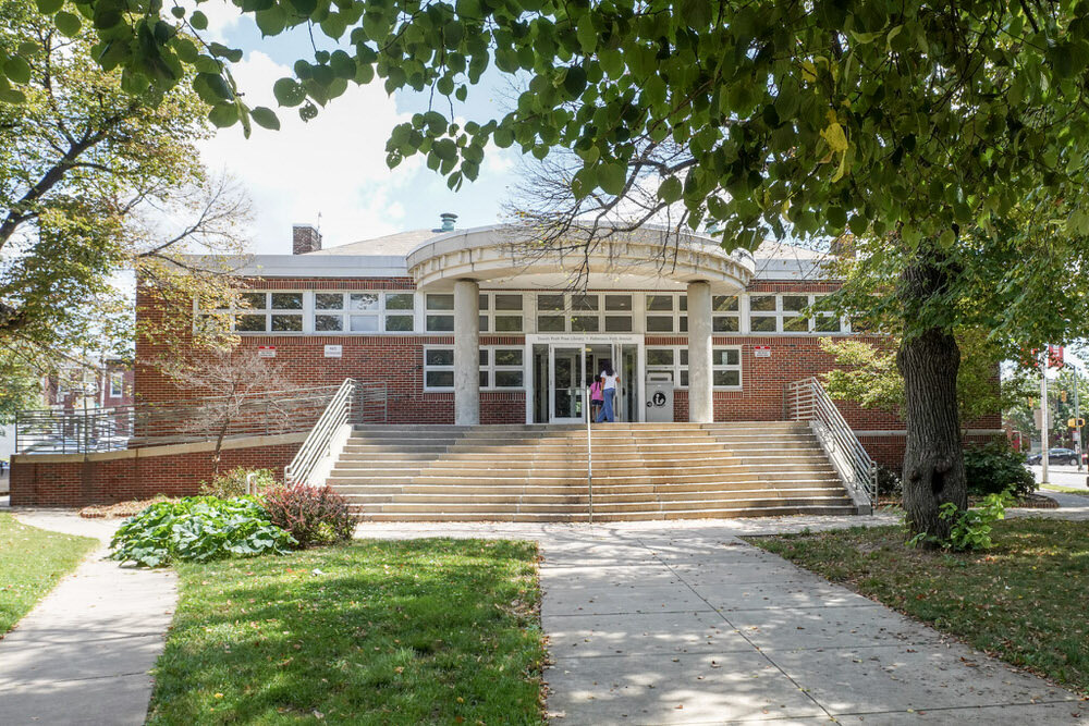 Patterson Park entrance with people at the door, steps, accessible ramp, grass, and trees