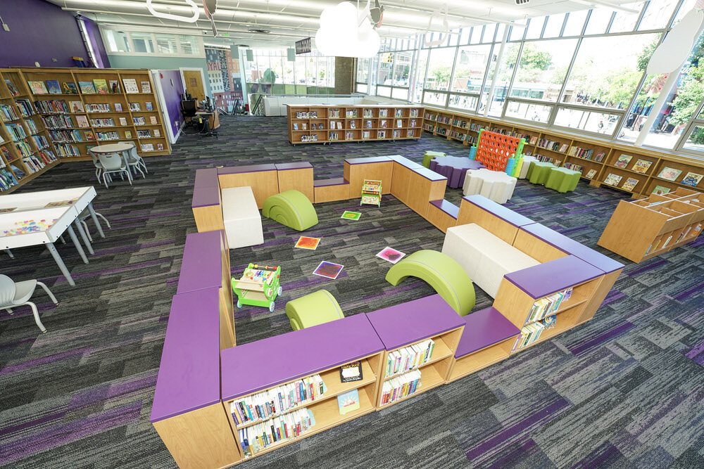 Pennsylvania Avenue Branch children's section by windows with new bookcases, colorful play zones, and soft furniture