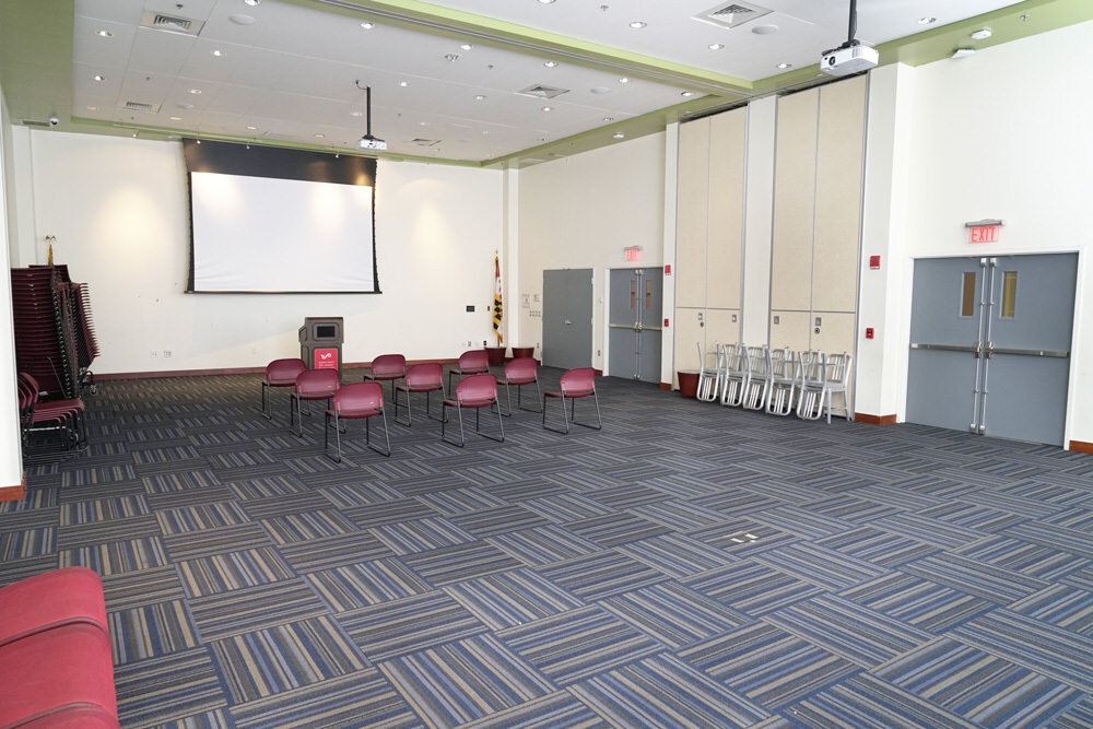 Southeast large meeting room - auditorium facing a corner with doors, chairs, and screen
