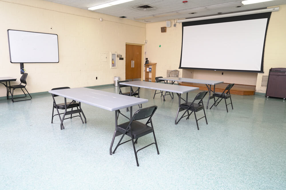 Walbrook meeting room with tables, chairs, a projection screen, and a whiteboard