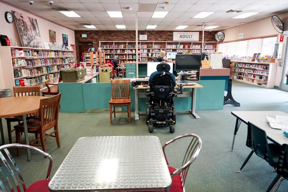 Washington Village adult section, tables and chairs, and a customer using a computer